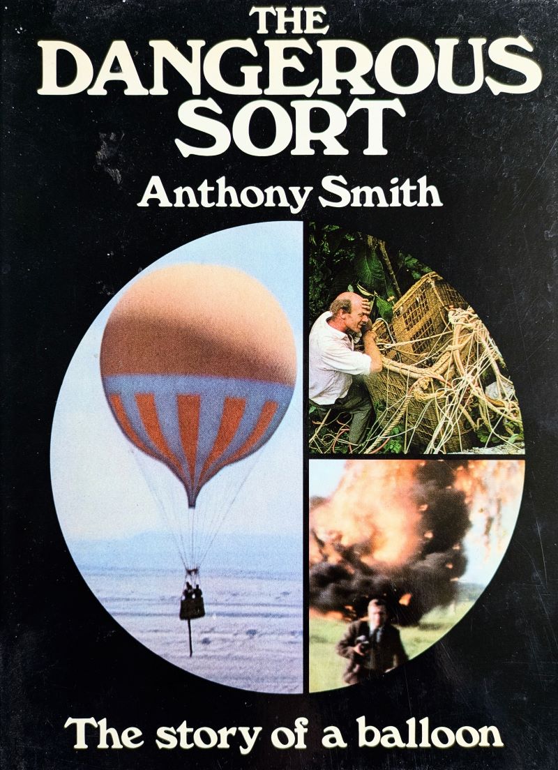 Picture of the black book cover showing 3 images in a circle - a gas balloon in the sky, a man holding on to a balloon basket in a tree and a man running away from a burning balloon on the ground.